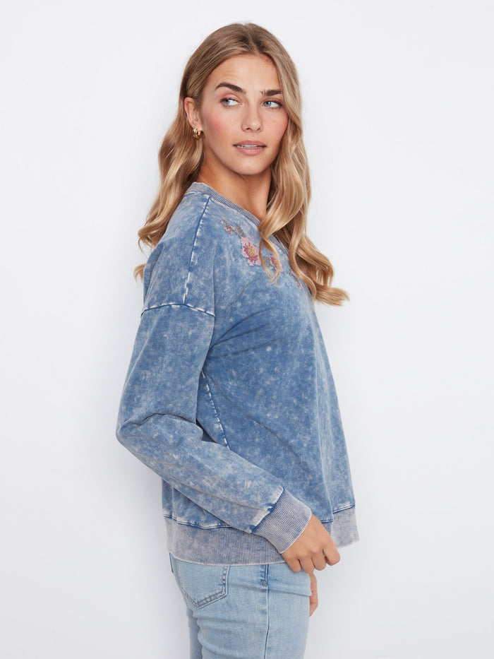 V-neck denim blue top with long sleeves and detailed floral embroidery, made from soft stretch cotton by Charlie B.