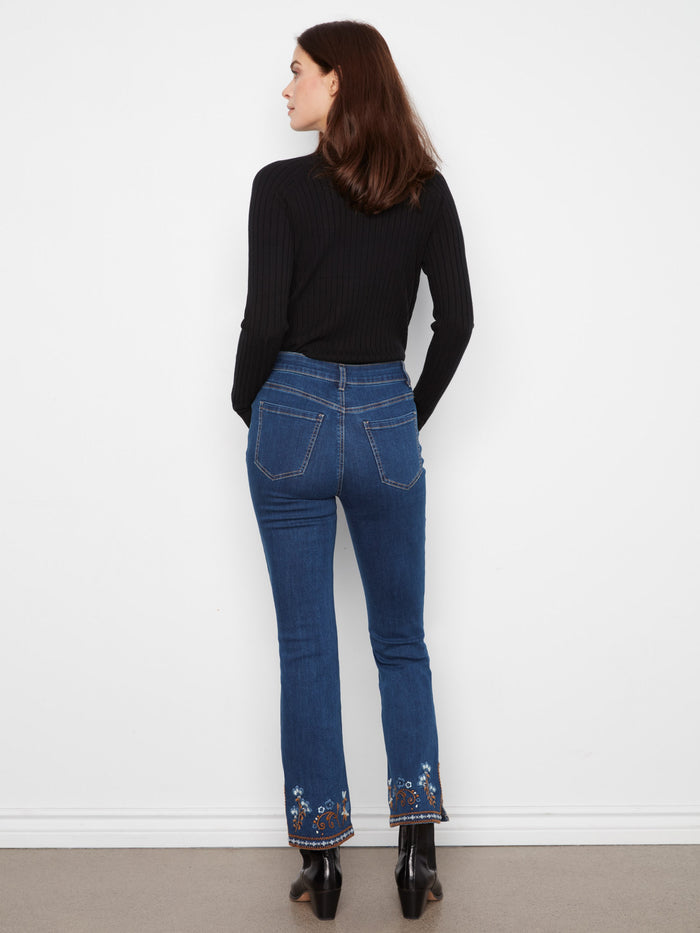 Intricate embroidery adorns the hem of these jeans, providing an elegant and artistic flair. Created by Charlie B.
