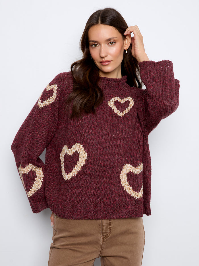 This burgundy sweater features a cozy mock neck design, perfect for keeping warm in style. Adorned with charming heart patterns by Charlie B.