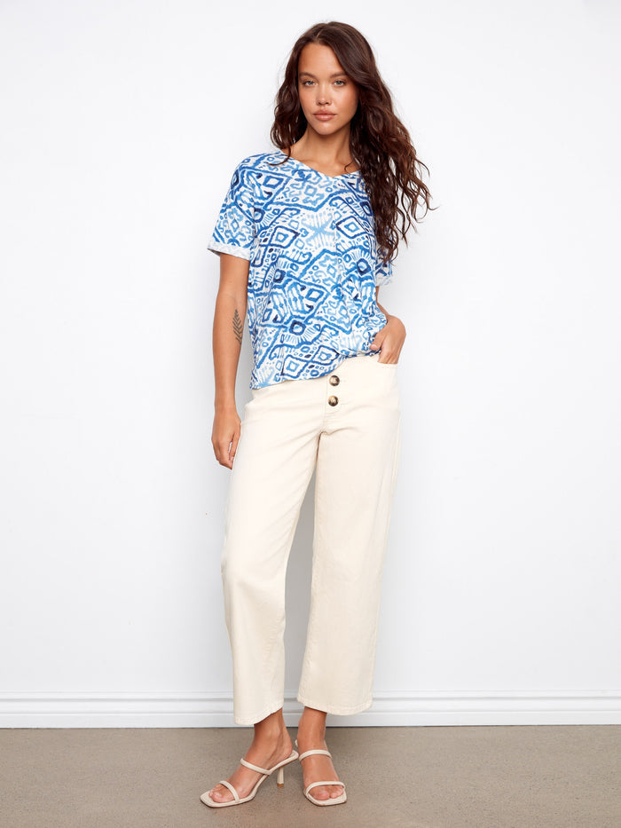 Stylish blue top featuring side knot detail and intricate patterns, matched with beige pants by Charlie B.