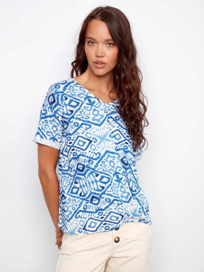Chic blue patterned top showcasing short sleeves, perfect for casual wear. Paired with beige pants by Charlie B.