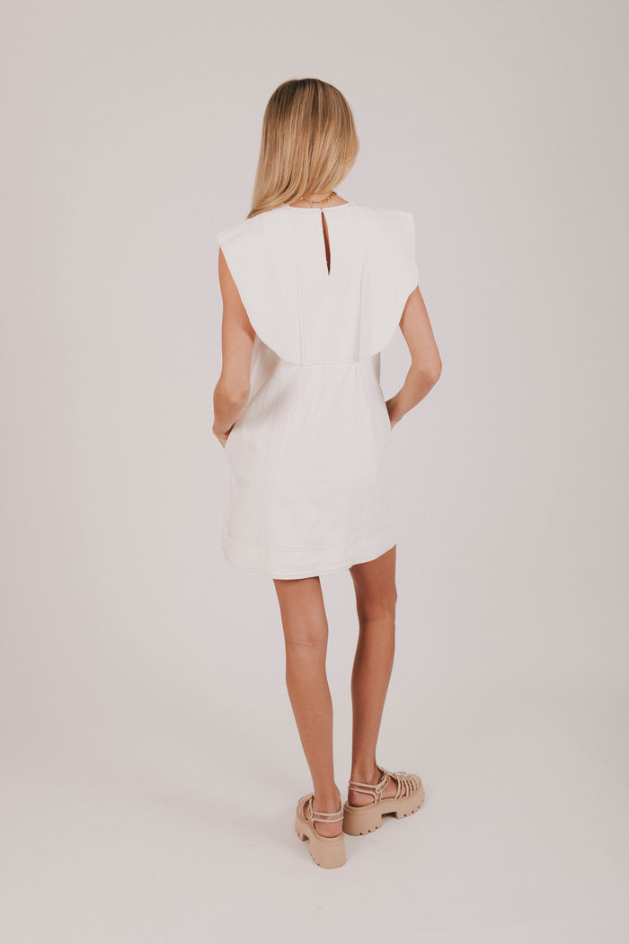 white mini dress with buttons down the front and a wide collar